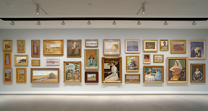 Installation view, Iconic Loved Unexpected, Newcastle Art Gallery, Australia, 2025, featuring (top row, left to right) Julian Ashton, Untitled, 1889; John Ford Paterson, Landscape with tree fern, 1892; Arthur Streeton, Belinda (Lady of the period),1894; Arthur Streeton, Australian December, the first crop, 1886–7, Rupert Bunny, The artist's wife and maid, c. 1900; Albert Henry Fullwood, Susan Island, 1894; George Bell, The beach, Corfe, 1912, Charles Bryant, Reflections, coast of Cornwall, c.1912, E. Phillips Fox, Nude, c.1910; Elioth Gruner, Spring morning, 1917; George W. Lambert, Newcastle station and Harbour, 1925; George W. Lambert, Portrait (Red trimmed hat), c.1921; (middle row, left to right) attributed to Julian Ashton, Woman in a kimono, 1895; W. C. Piguenit, A conversazione, c.1896; Sophie Steffanoni, The incoming tide, Sydney Harbour, 1898; Edith Cusack, Evening, Darling Harbour, 1896; Rupert Bunny, Sunshine c.1910; Hilda Rix Nicholas, French peasant woman c.1912, attributed to Julian Ashton, Portrait, 1913; Charles Bryant, Sketch for summer sea, 1931; (bottom row, left to right) W. Lister Lister, Bush scene, c.1900; Sydney Long, In the spring, c.1895; Jane Sutherland, Heidelberg landscape, c.1892; Rupert Bunny, Last fine days, Royan, c.1908; W. Lister Lister, Sunshine c.1910; Rupert Bunny, Portrait of the artist’s niece, 1912, George W. Lambert, Cavalry approaching an Arab village, 1920; Hilda Rix Nicholas, Grace, c.1914; Hilda Rix Nicholas, The Spanish shawl, c.1936; James Quinn, Portrait of the artist’s wife, 1926 / ‘Australian Modernism,’ Location: Valerie and John Ryan Gallery (Gallery 4) / Newcastle Art Gallery Collection / Photograph: Matt Carbone